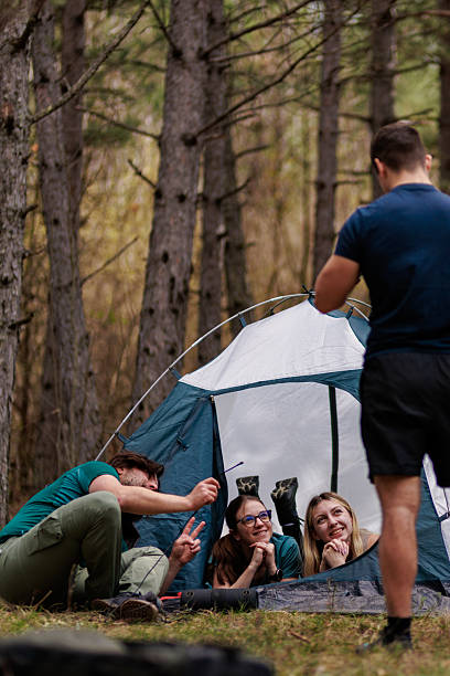istock Friends enjoying a fun camping experience inside a tent surrounded by nature on a beautiful day 2239648411