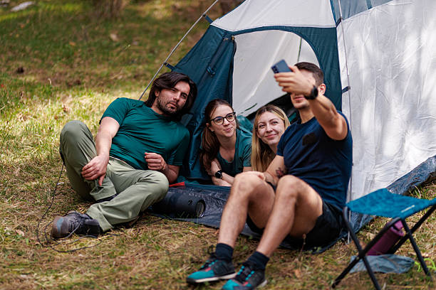 istock Friends enjoying a fun camping trip together in nature while taking selfies and relaxing by their tent on a sunny afternoon 2239648439