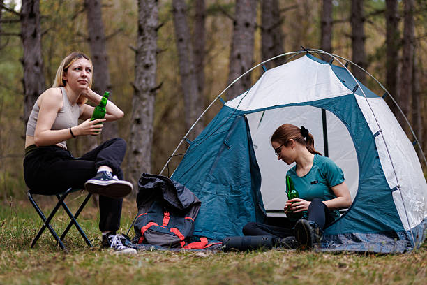 istock Friends enjoy a relaxing camping trip in the woods while sipping drinks and taking a break from their outdoor adventure 2239648449