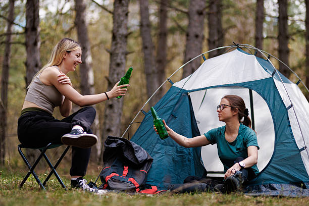 istock Friends enjoy drinks while camping in a serene forest setting during a sunny afternoon surrounded by tall trees 2239648470