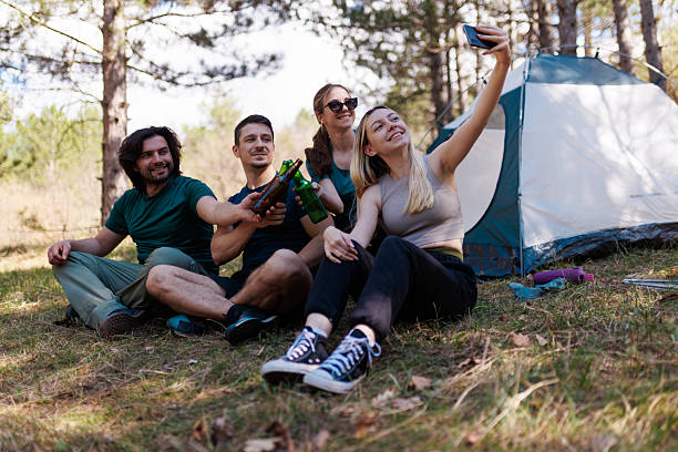 istock Friends enjoying a relaxing camping experience while taking selfies in a serene forest location on a sunny day 2239648475