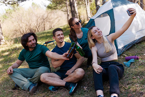 istock Friends enjoying a sunny camping trip while taking selfies and sharing drinks in a beautiful forest setting 2239648506
