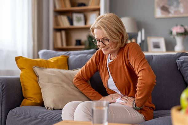 istock Thoughtful Woman Sitting on Sofa Holding Her Stomach 2239649565