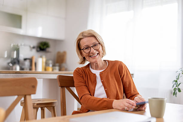 istock Happy senior woman smiling while using a mobile phone indoors. 2239649566
