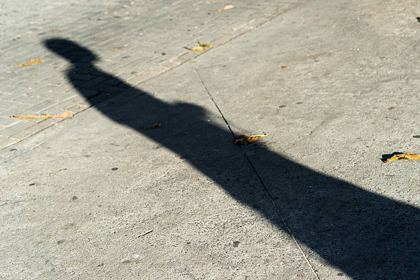 istock A persons long shadow on a concrete sidewalk with autumn leaves 2239660157