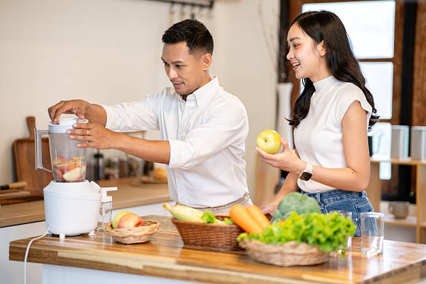 istock Asian man using blender making smoothie drink while woman holding apple watching at kitchen counter 2239667209
