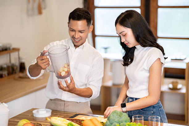 istock Asian man looking at blender while woman knife cutting apple making smoothie drink at kitchen counter. 2239667211