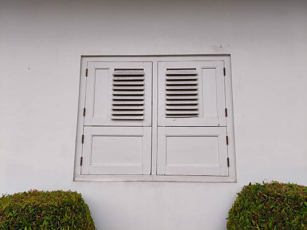White Window with Louvered Shutters on a White Wall
