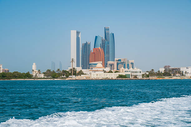 First person view from a moving boat showcases the impressive Abu Dhabi downtown waterfront, highlighting the city's modern, sleek architecture and the grandeur of the iconic Emirates Palace. The scene captures the essence of luxury and contemporary development in the capital of the UAE.