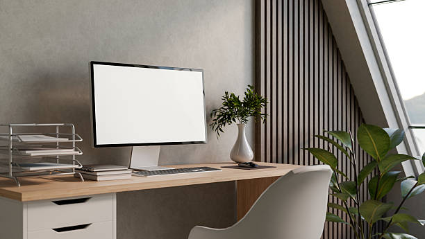 istock Blank screen computer on wooden table with book and vase aside loft wall in a bedroom or living room 2239673344