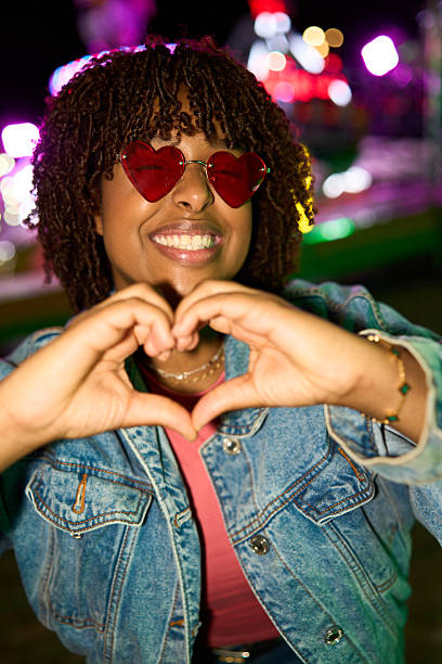 istock Woman making heart hand gesture at night carnival 2239674585