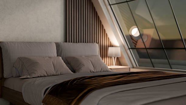 istock Dim lit modern bedroom with pillows and blanket under lamp light on side table and large roof window 2239676085