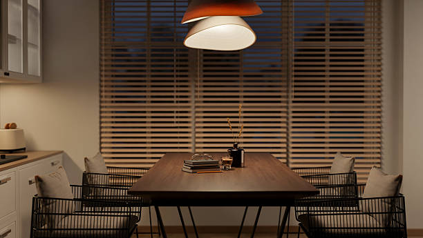 istock Coffee cup and book on wooden table under lamp in a kitchen or dining room with blind covered window 2239680224