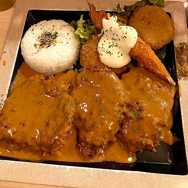 Crispy tonkatsu, a Japanese-style breaded and deep-fried pork cutlet, served with shredded cabbage and drizzled with savory sauce. A delightful balance of crunchy texture and juicy meat.