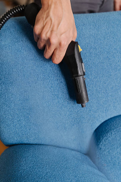istock Homeowner using steam cleaning machine, removing tough stains from upholstered blue couch in modern living space, maintaining pristine furniture condition, close-up. 2239686001