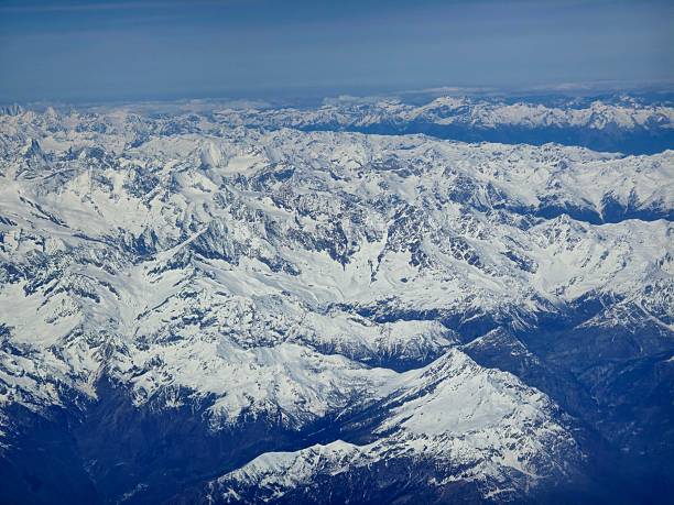 Several mountain peaks in the Swiss Alps. The image was captured on a commercial flight during spring season.