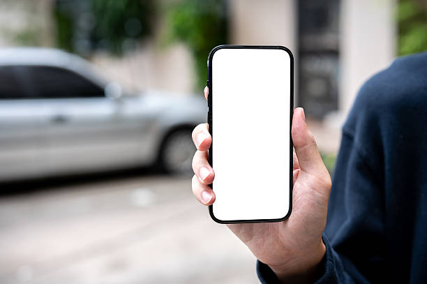 istock Close up of man's hand holding and showing white screen smartphone while standing in parking lot. 2239687208