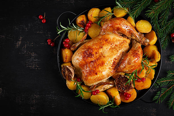 istock Baked chicken or turkey. Roasted chicken with potatoes and Christmas decoration.  Table setting. Top view, closeup 2239687575