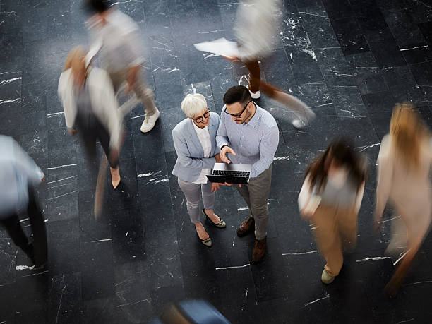 istock Above view of entrepreneurs using laptop among colleagues in blurred motion. 2239687709