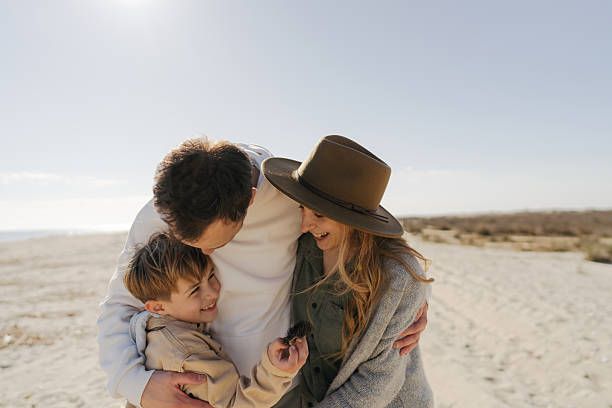 Photo of a young family, catching some winter sun on the local beach by the ocean