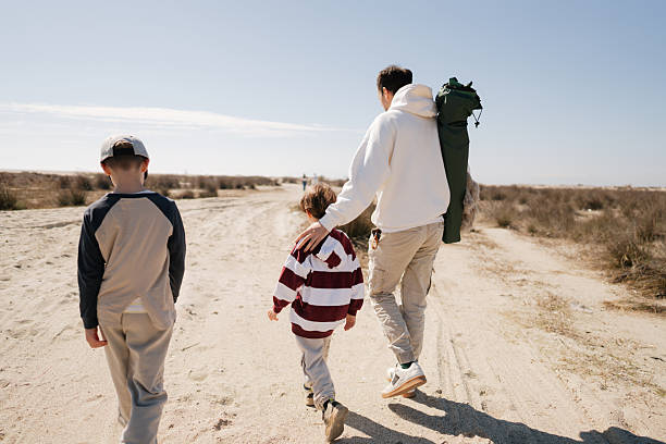Photo of a father and his two young boys, looking for a perfect spot for picnic on the local beach