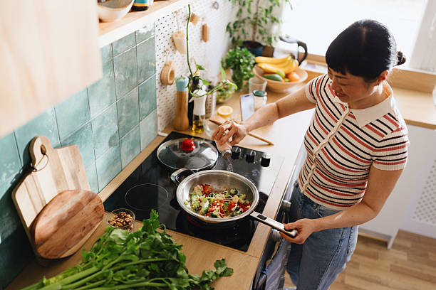 istock Woman adding spices to vegetables in a frying pan 2239693793