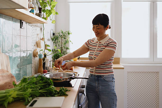 istock Woman adding fresh vegetables into a frying pan 2239693795