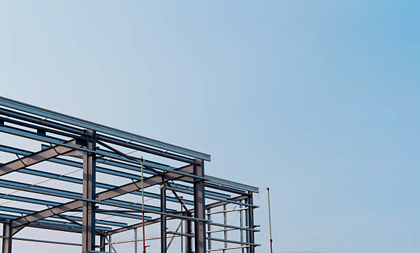 istock Steel beams form the skeletal steel frame structure of a building under construction, contrasting with a bright blue sky 2239694685
