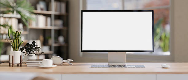istock White screen computer with coffee cup aside books and potted plants on wooden table in a living room. 2239698606