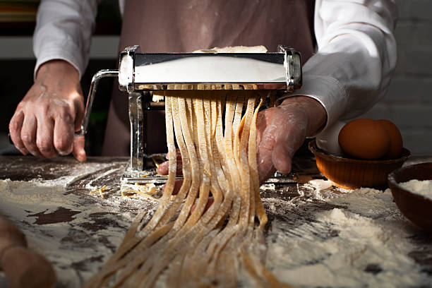 istock Caucasian female hands making fettuccine noodles using mechanical pasta machine 2239701245