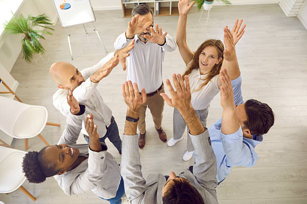 istock Successful business people on corporate team building training standing with hands up in office. 2239701675