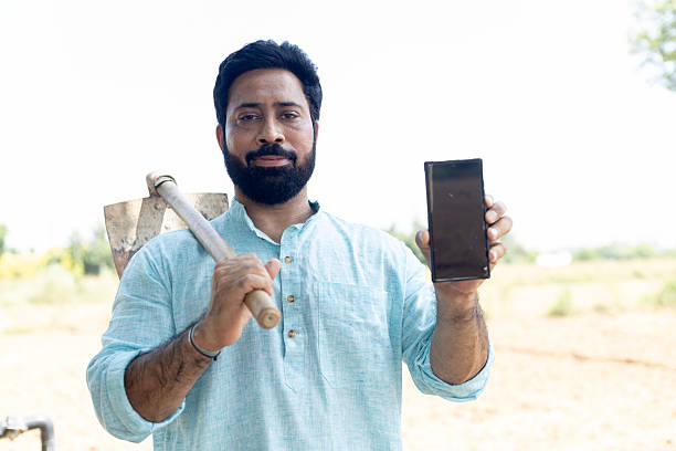 Indian farmer showing mobile phone in field