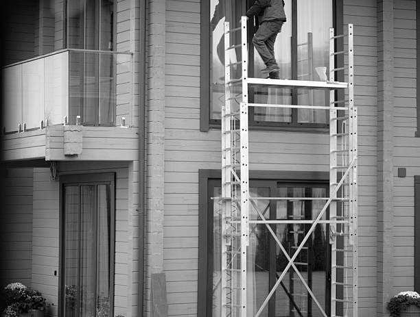 manual workers hanging outside office building cleaning glass wall