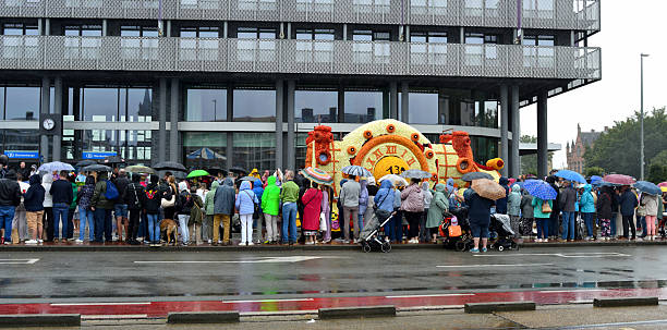 Blankenberge, West-Flanders, Belgium - August 31, 2025: At the end of summer, tourists in the rain watch the flower parade passing by in front of station building and Mercure hotel. 130 years of tradition