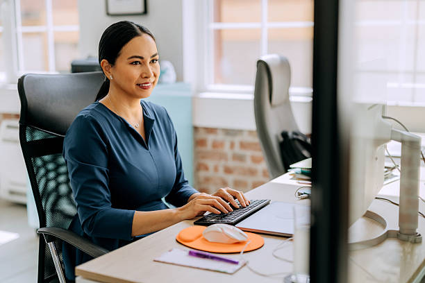 istock Well-dressed businesswoman working on desktop PC at office 2239707623