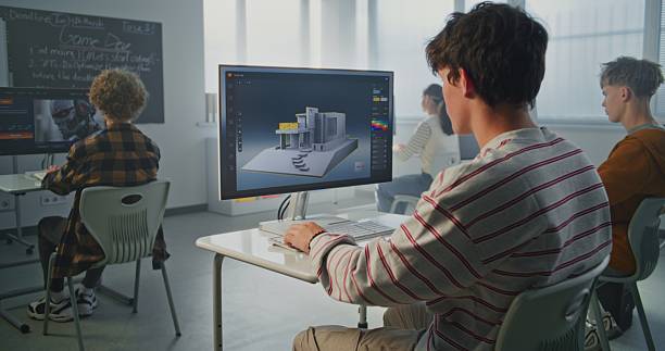istock Young Man with Dark Hair Concentrates on 3D House Design at Computer in Classroom 2239710362