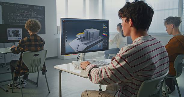 istock Young Man with Dark Hair Concentrates on 3D House Design at Computer in Classroom 2239710611