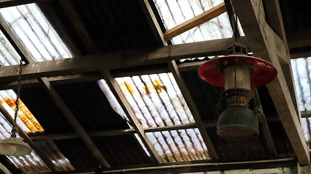 istock Old kerosene lamp hangs beneath a weathered corrugated metal roof with translucent panel 2239714507