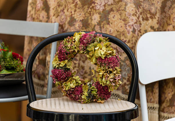 Rustic floral wreath on vintage black chair with cozy patterned background, lifestyle