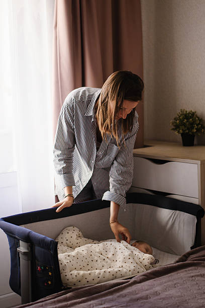 istock Mother Gently Caring For Newborn In Bedside Crib 2239715031