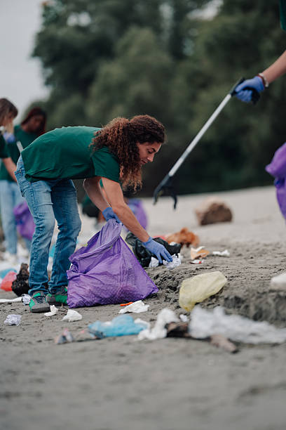 istock Volunteer cleaning beach, picking up plastic pollution and litter 2239718300