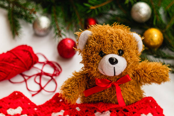 Teddy Bear with a red bow near the Christmas tree and bright balls.
