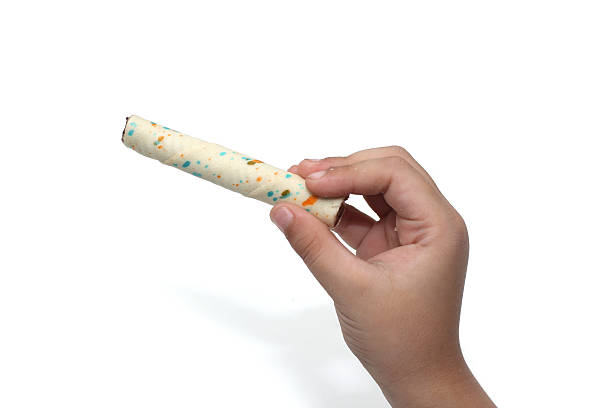 child's hand holding vanilla wafer stick isolated on white background