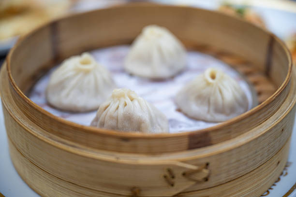 Close-up of freshly steamed dumplings served in a bamboo basket at a restaurant, showcasing authentic Asian cuisine and elegant food presentation.
