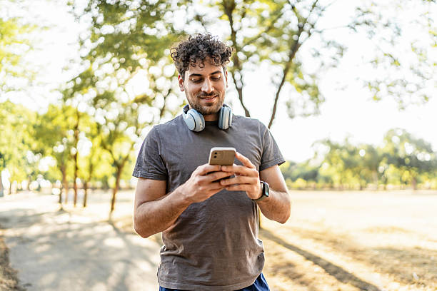 istock Young adult man checking smartphone in park 2239724908