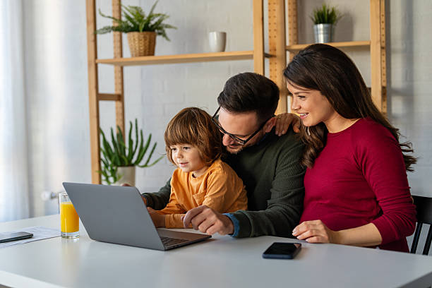 istock Parents and child relaxing at home with computer watching funny internet video, making online call 2239726433