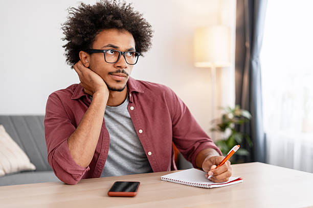 istock Young man thinking and writing, finding inspiration at home 2239727276