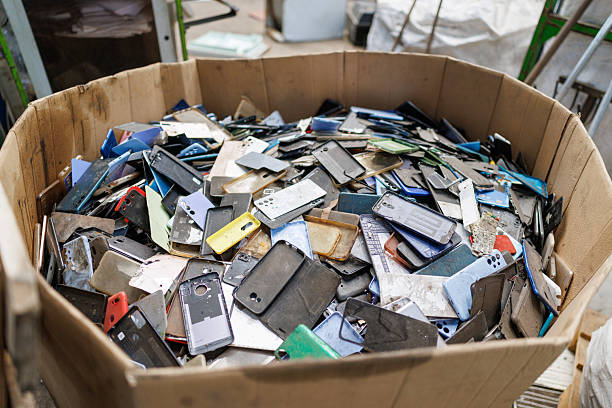 Assorted smartphone parts and accessories, including old devices, screens and colorful phone cases, collected as part of electronic waste processing