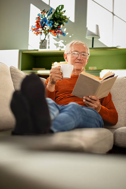 istock Senior man enjoying a calm afternoon at home while reading a book and sipping tea 2239733452