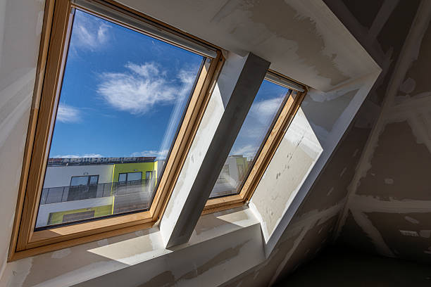 istock Two large skylight windows with wooden frames in an unfinished attic space under construction. Natural light enters the room, highlighting the drywall and modern architectural design. 2239734277